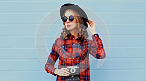 Portrait of young woman photographer with vintage film camera wearing a black round hat