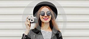 Portrait of young woman photographer with vintage film camera on white background