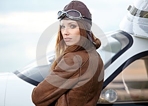 Portrait of young woman pilot in front of airplane.