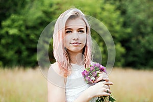 Portrait of a young woman with pink hair and a clover bouquet, close-up