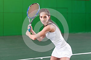 Portrait of a young woman playing tennis on court.