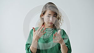 Portrait of young woman pointing at camera then making Call Me hand gesture on white background