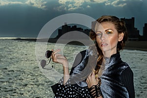 Portrait of young woman posing on the pier, with effective clouds and lighting from coming thunderstorm.