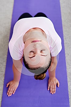 Portrait of young woman practicing yoga at home indoor, copy space. Girl stretching on mat, full length. Relaxing and doing yoga.