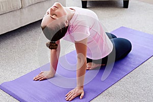 Portrait of young woman practicing yoga at home indoor, copy space. Girl stretching on mat, full length. Relaxing and doing yoga.