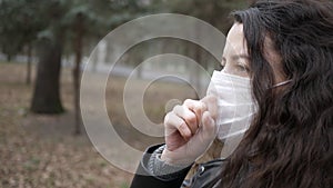 Portrait of young woman in protective mask walking through city. Coughs. Pandemic coronavirus