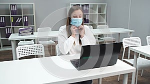 Portrait young woman puts on medical mask and looking at camera in office. Medical Protection at Work