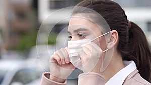 Portrait of young woman puts on medical mask to face going out to street