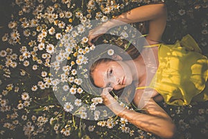 Portrait of young woman with radiant clean skin lying down amid flowers on a lovely meadow