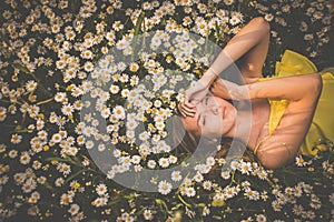 Portrait of young woman with radiant clean skin lying down amid flowers on a lovely meadow