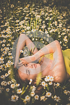 Portrait of young  woman with radiant clean skin lying down amid flowers on a lovely meadow