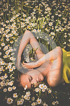 Portrait of young  woman with radiant clean skin lying down amid flowers on a lovely meadow