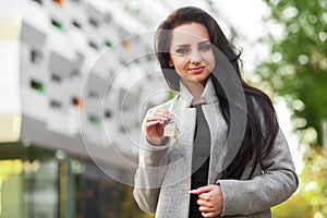 Portrait of a young woman realtor or businesswoman standing outdoors on the modern residential district background