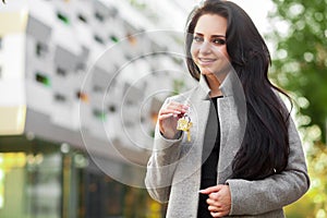 Portrait of a young woman realtor or businesswoman standing outdoors on the modern residential district background