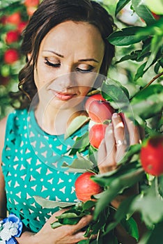 Portrait of young woman with red apple in garden