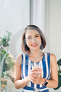 Portrait of young woman relaxing near the door and holding a cup of coffee/tea