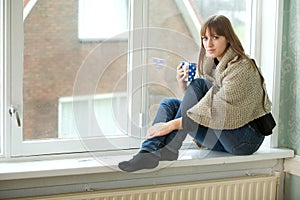 Young Woman Relaxing by Window with Cup of Tea