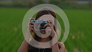 Portrait of a young woman with a retro camera in the rice field