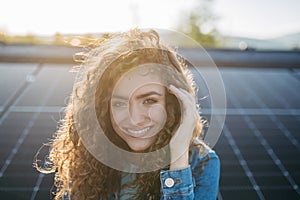 Portrait of young woman on roof with solar panels.