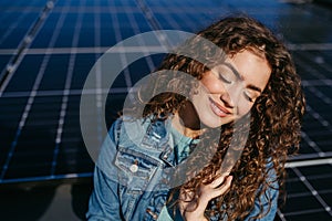 Portrait of young woman on roof with solar panels.