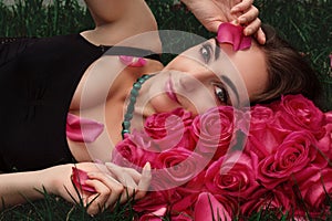 Portrait of a young woman in roses on the grass. Art portrait.