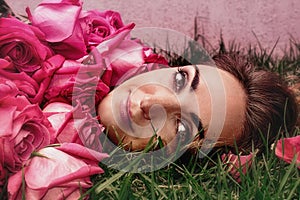 Portrait of a young woman in roses on the grass. Art portrait.