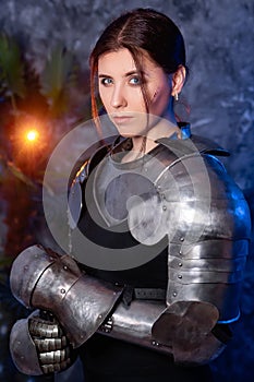 Portrait of a young woman with scars on her face, dressed in black clothes with steel knightly hands and a gorget