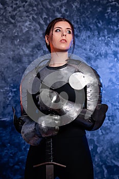 Portrait of a young woman with scars on her face, dressed in black clothes with steel knightly hands and a gorget