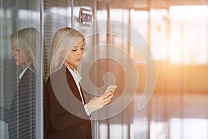 Portrait of young woman sending message on smartphone in office. Copy space.