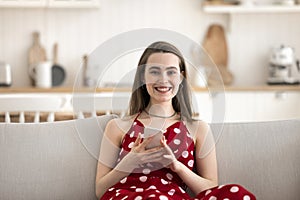 Portrait of young woman sit on sofa use modern smartphone