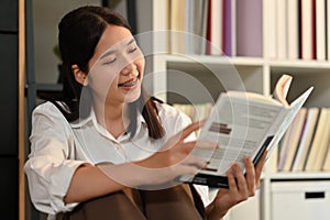 Portrait of young woman sitting floor in living room and reading books. People, leisure and lifestyle concept