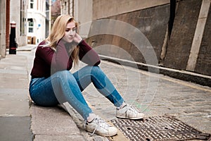 Portrait of young woman sitting on the floor and looking melancholic
