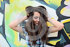 Portrait of young woman sitting at graffiti wall