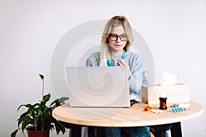 Portrait of young woman sitting near laptop, pills blisters, having video call with doctor online. Online consultation.