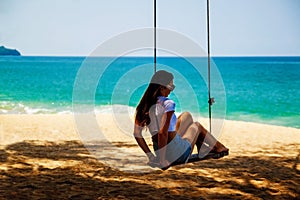 Portrait Young Woman Sitting On Swing Rope And Sea Around Beach