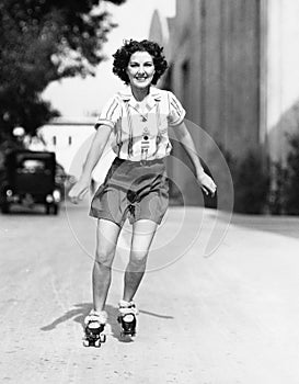 Portrait of a young woman skating on the road and smiling