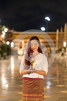 portrait young woman is smileing holding candle and praying at Wat