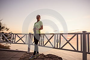 Portrait of young woman in sportswear, stopped for break between workouts. Sportswoman looks at dawn