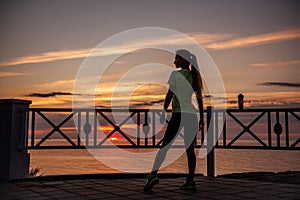 Portrait of young woman in sportswear, stopped for break between workouts. Sportswoman looks at dawn