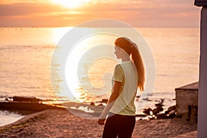 Portrait of young woman in sportswear, stopped for break between workouts. Sportswoman looks at dawn