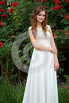 Portrait of young woman in the spring time. Almond flowers blossoms. Girl dressed in white like a bride. rose Garden