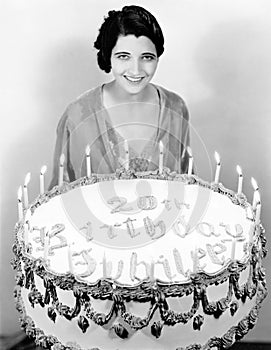 Portrait of a young woman standing in front of a birthday cake