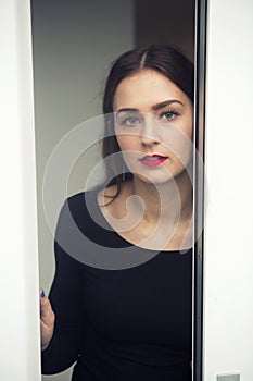 Portrait of young woman standing by open window