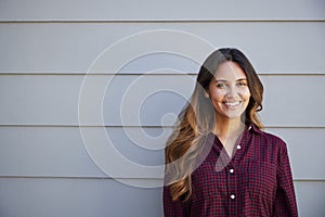 Portrait Of Young Woman Standing Outside Grey Clapboard House