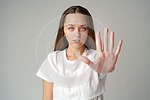 Portrait of a young woman standing with outstretched hand showing stop gesture on gray background