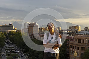 Portrait of young woman standing at sunset in city of Yerevan viewpoint
