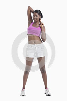 Portrait of young woman stretching arms over white background