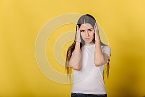 Portrait of young woman in studio has sort of a headche. Woman put hand on head. Hard working and hard day. Yellow