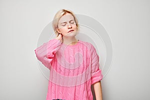 Portrait of young woman suffering from pain, touching neck isolated on white studio background. Psychosomatics of stress