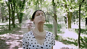 Portrait young woman in summer Park, she removes protective mask from his face and inhales deeply enjoying fresh air